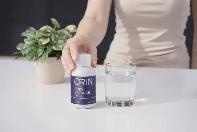 Žena připravuje ORIN BODY BALANCE rostlinný komplex se sklenicí vody